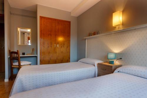 a bedroom with two beds and a desk with a chair at HostalTina in Bossost