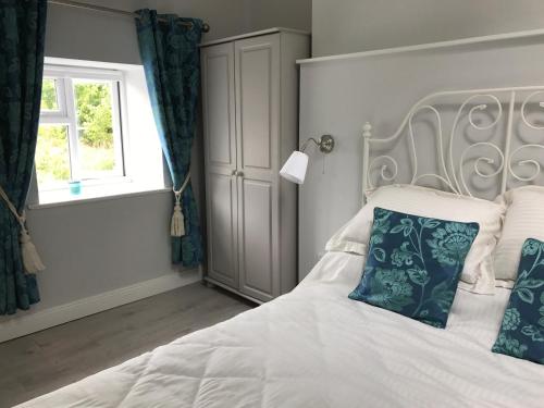a bedroom with a white bed with blue pillows and a window at Hobbit Hollow in Ballymore Eustace