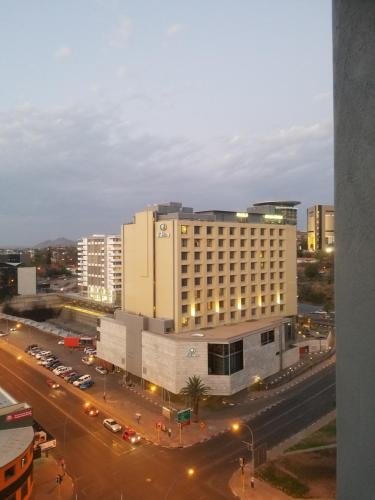 a large building with a parking lot in front of a street at 77 On Independence Apartments in Windhoek