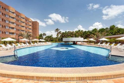 uma grande piscina com cadeiras e guarda-sóis em Aptos Gran Lencois Flat Res. em Barreirinhas