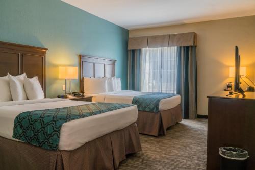 una camera d'albergo con due letti e una finestra di Heritage Place Hotel and Suites a DeQuincy