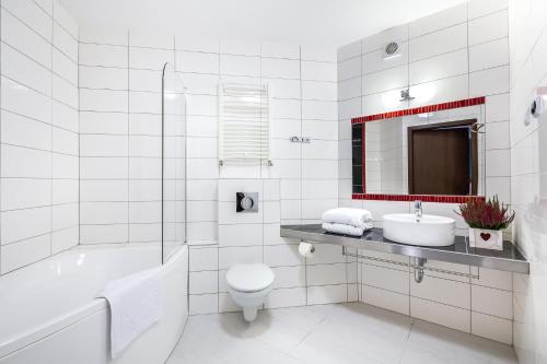 biała łazienka z wanną, toaletą i umywalką w obiekcie Krasicki Hotel Resort & Spa w Świeradowie Zdroju