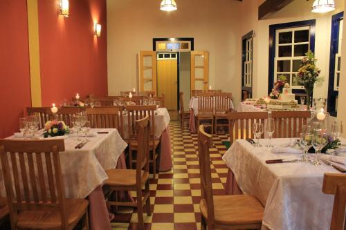 a restaurant with several tables with white tablecloths at Pousada Villa Parahytinga in São Luiz do Paraitinga