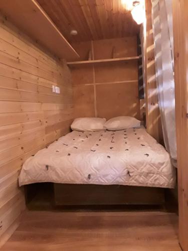 ein kleines Bett in einem Zimmer mit Holzwänden in der Unterkunft Namiņš in Jurģi