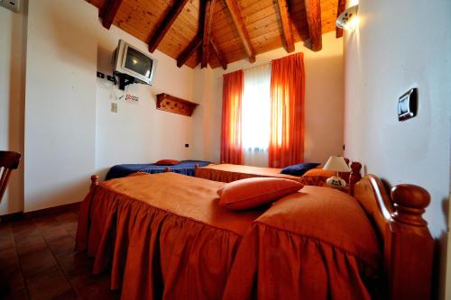 a bedroom with three beds with orange sheets at Agriturismo Le oche selvatiche in Lauzacco