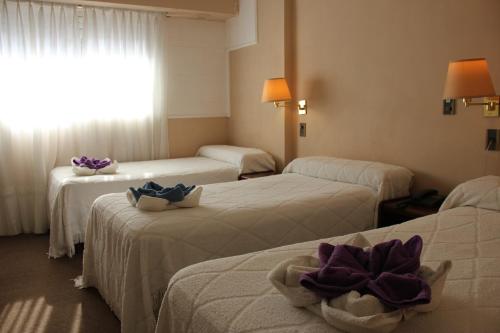 a hotel room with three beds with towels on them at Hotel Bertaina in Santa Fe