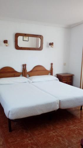 a bedroom with two white beds and a mirror at Hotel Los Perales in Puebla de Sanabria