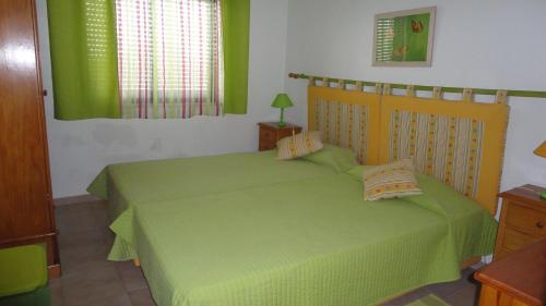 a bedroom with a bed with a green bedspread at Apt com piscina em Alporchinhos in Lagoa