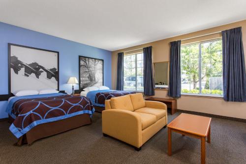 a hotel room with two beds and a chair at Super 8 by Wyndham Smithfield-Selma in Smithfield