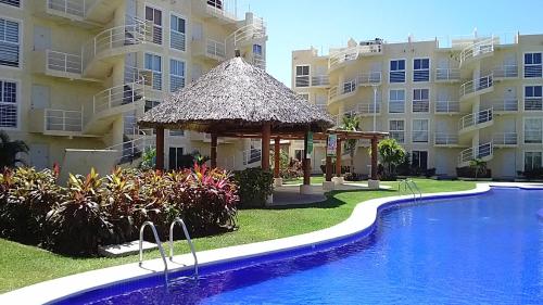 uma piscina com um gazebo ao lado de alguns edifícios em marina diamante iris em Acapulco