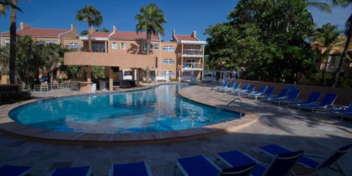 a swimming pool with blue chairs and a building at Divi Dutch Village Beach Resort in Palm-Eagle Beach