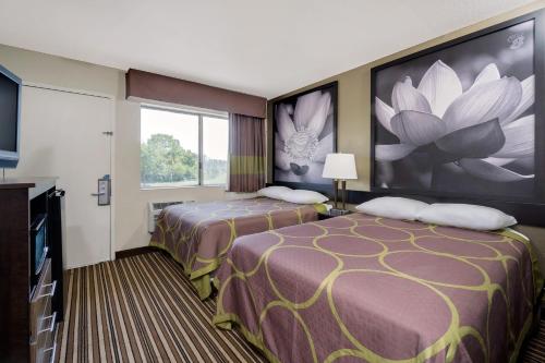 una camera d'albergo con due letti e un grande dipinto sul muro di Super 8 by Wyndham Florence a Florence