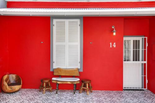 a red wall with a chair and two stools at Backup-Powered Art Deco Cottage in De Waterkant in Cape Town