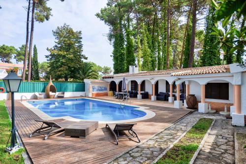 uma casa com uma piscina e um deque de madeira em Verdizela Pool & Garden em Charneca