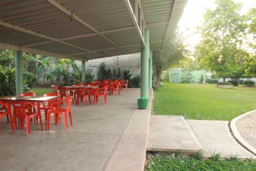 a row of red tables and chairs under a pavilion at Hotel Puuc in Oxkutzcab
