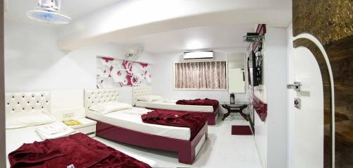 2 Betten in einem Zimmer mit roter Bettwäsche in der Unterkunft Hotel Pearl in Navi Mumbai
