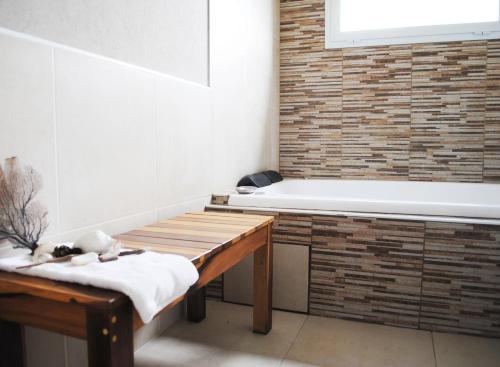 La salle de bains est pourvue d'une baignoire et d'un banc en bois. dans l'établissement Médano 29 Departamentos en alquiler, à Las Gaviotas