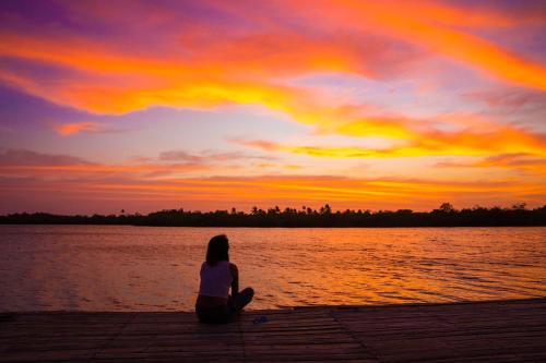 a woman sitting on a dock watching the sunset at Tintipan Cabana SalSiPuedes in Tintipan Island