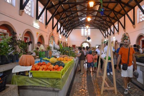a group of people walking around a market with fruits and vegetables at Casa Pelourinho in Silves