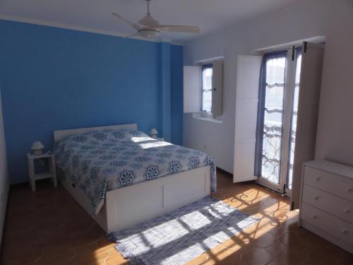 een blauwe slaapkamer met een bed en een raam bij Casa Pelourinho in Silves