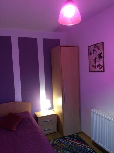 a purple bedroom with a bed and a lamp at Pokoje Goscinne Oliwia & Laura II in Rumia
