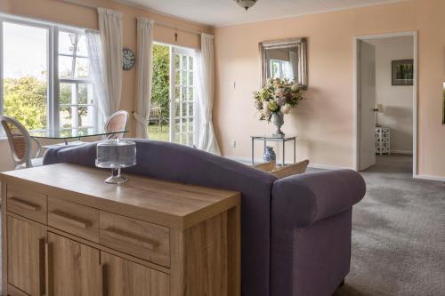 a living room with a blue couch and a table at The Whitehouse of Marybank in Nelson