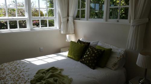 een bed in een slaapkamer met 2 ramen bij The Whitehouse of Marybank in Nelson