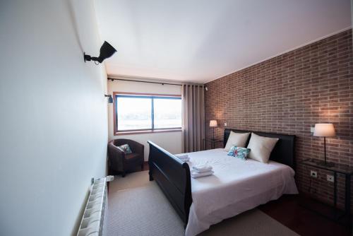 ein Schlafzimmer mit einem Bett und einer Ziegelwand in der Unterkunft Douro Balcony Apartment in Porto