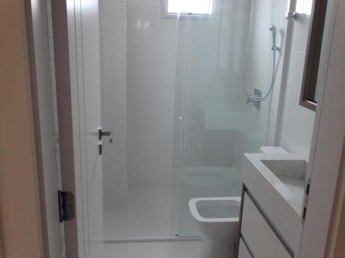 a bathroom with a shower and a toilet and a sink at Apartamento Avenida F in Bombinhas