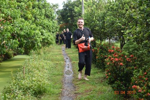 a man walking down a path with a red bag at Mekong Rustic Cai Be in Cai Be
