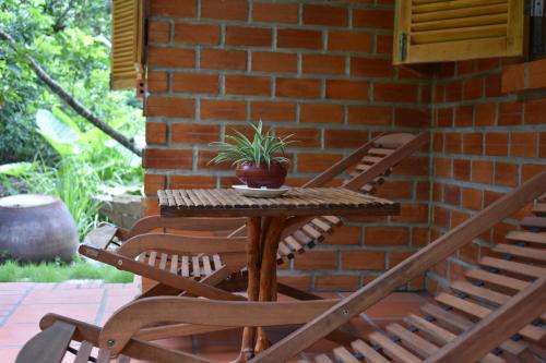 a table with two chairs and a potted plant on a patio at Mekong Rustic Cai Be in Cai Be