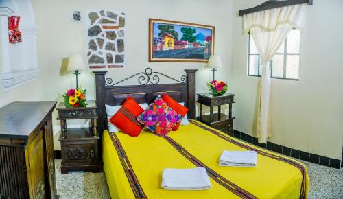 a bedroom with a large bed with yellow sheets and red pillows at Posada San Vicente by AHS in Antigua Guatemala