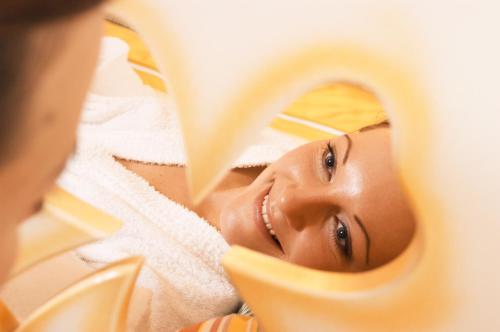 a woman looking at her face in a mirror at Wanderhotel Kirchner in Bramberg am Wildkogel