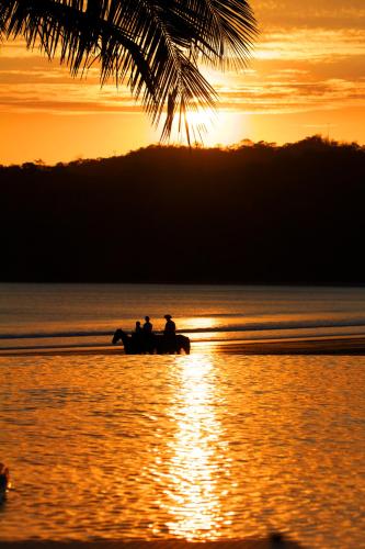 two people riding horses on the beach at sunset at Playa Venao Hotel Resort in Playa Venao
