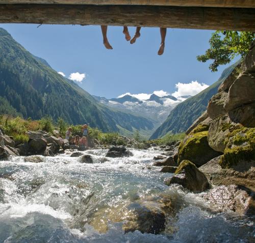 a river under a bridge with mountains in the background at Wanderhotel Kirchner in Bramberg am Wildkogel