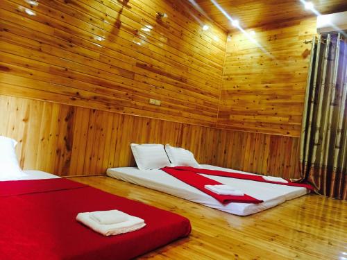 two beds in a room with wooden walls and wooden floors at Bac Ha Lake View in Bắc Hà