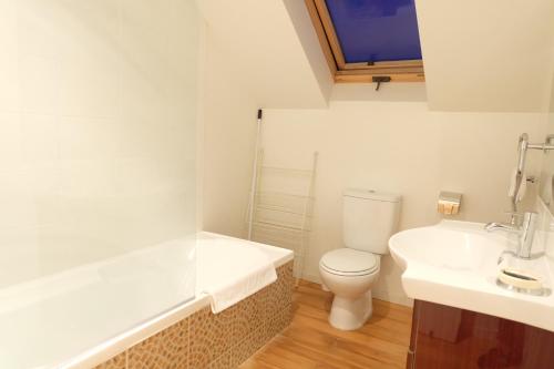 Baño blanco con aseo y lavamanos en BeachLife Apartments en Christchurch