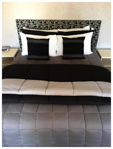 a bedroom with a large bed with black and white pillows at Deco City Motor Lodge in Napier