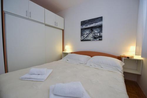 a bedroom with a large white bed with two towels on it at Vicy Apartment Novalja in Novalja