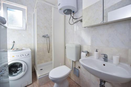 a bathroom with a toilet and a sink and a washing machine at Vicy Apartment Novalja in Novalja