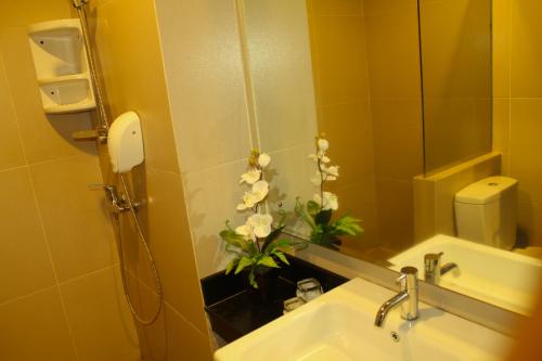 a bathroom with a sink with a vase of flowers at Drego Hotel in Pekanbaru