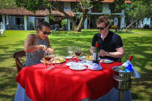 a man and a woman sitting at a table with wine glasses at Club Villa in Bentota
