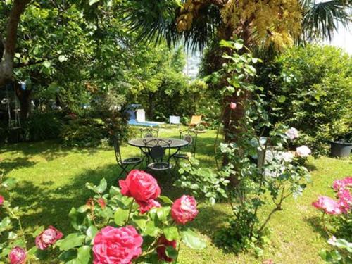 a garden with a table and roses in the grass at casa la resega in Gravedona