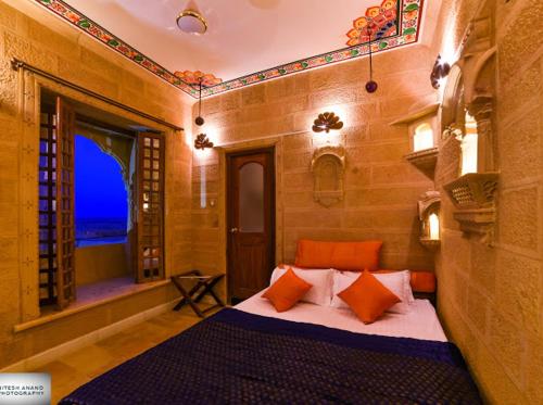 a bedroom with a bed with orange pillows and a window at Fort Villa in Jaisalmer