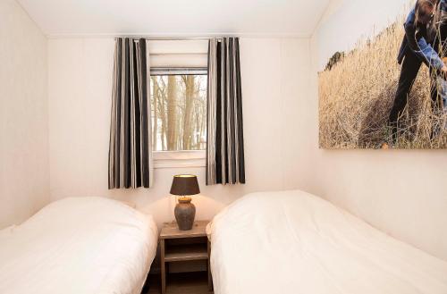 two beds in a small bedroom with a window at Hoeve Springendal Erf&Bron in Hezingen