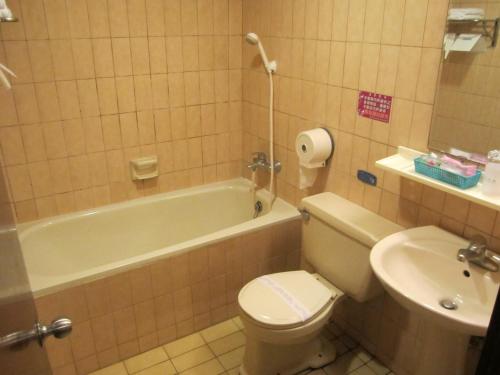 a bathroom with a toilet and a tub and a sink at Goshen Hotel in Kaohsiung