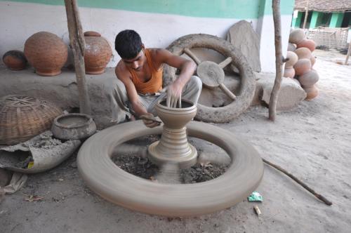 a man making a vase on a pottery wheel at The Riverwood Forest Retreat Pench in Khawāsa