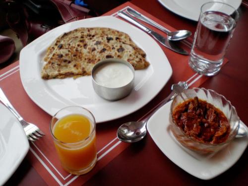 a table with a plate of food on a table at Hotel Mountain face by Snow City Hotels in Manāli