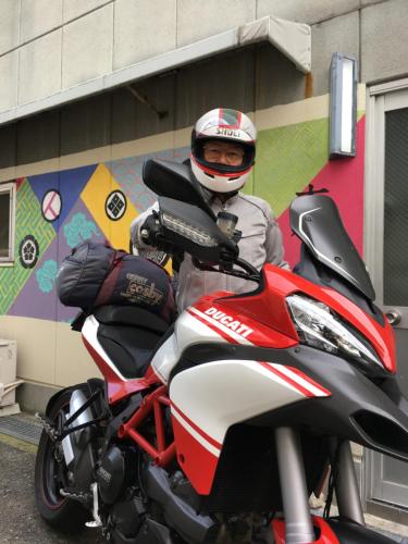 a man wearing a helmet sitting on a motorcycle at Music Uni Street Backpacker's Hostel in Toyonaka
