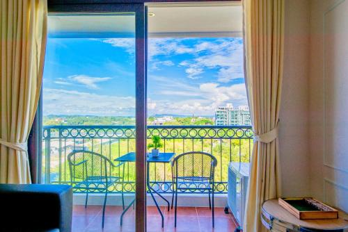 a room with a balcony with a table and chairs at Venetian Resort Pattaya in Jomtien Beach